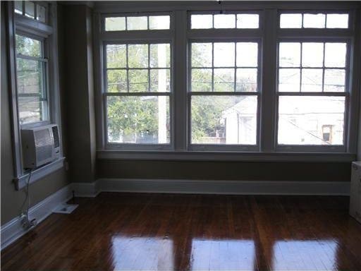 unfurnished room with dark hardwood / wood-style flooring, plenty of natural light, and cooling unit