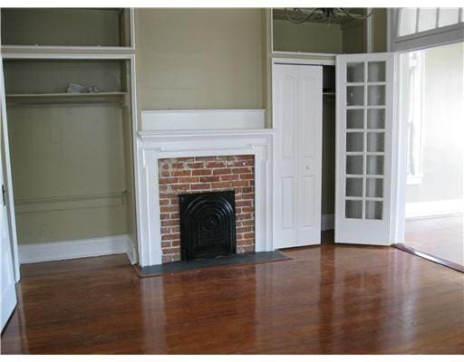 1127 Fern St, New Orleans, LA 70118 - unfurnished living room with wood finished floors and a brick fireplace