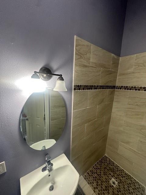 bathroom featuring a tile shower and sink