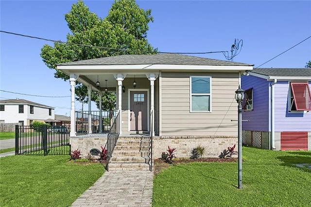 bungalow featuring brick siding, a shingled roof, fence, and a front yard