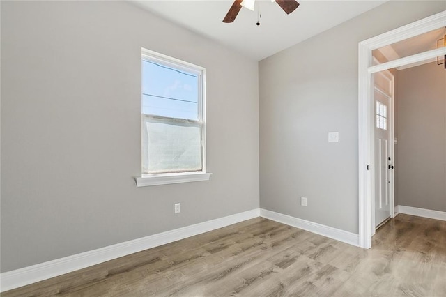spare room featuring a wealth of natural light, baseboards, ceiling fan, and light wood finished floors