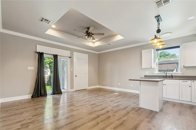 kitchen with visible vents, a center island, hanging light fixtures, white cabinetry, and a sink