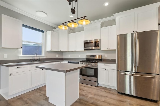 kitchen featuring stainless steel appliances, dark countertops, hanging light fixtures, a sink, and a kitchen island