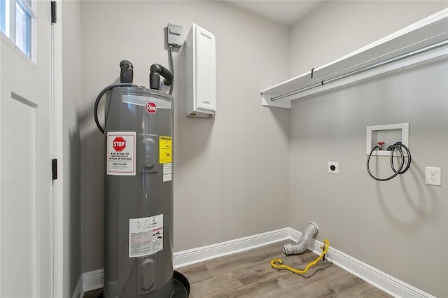 clothes washing area featuring hookup for a washing machine, electric water heater, hookup for an electric dryer, wood finished floors, and baseboards
