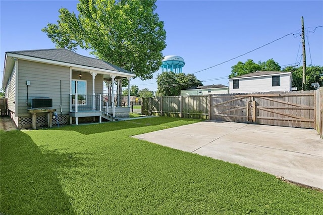 view of yard featuring covered porch, fence, and a gate