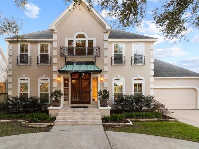 view of front of house featuring a garage, a balcony, and french doors