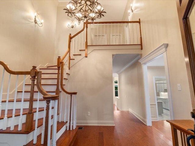 stairway with hardwood / wood-style floors, a notable chandelier, and crown molding