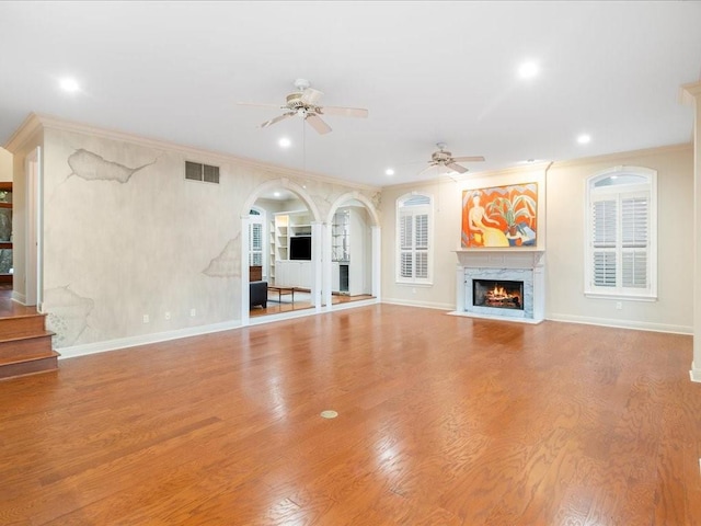 unfurnished living room with a high end fireplace, light hardwood / wood-style flooring, and ceiling fan