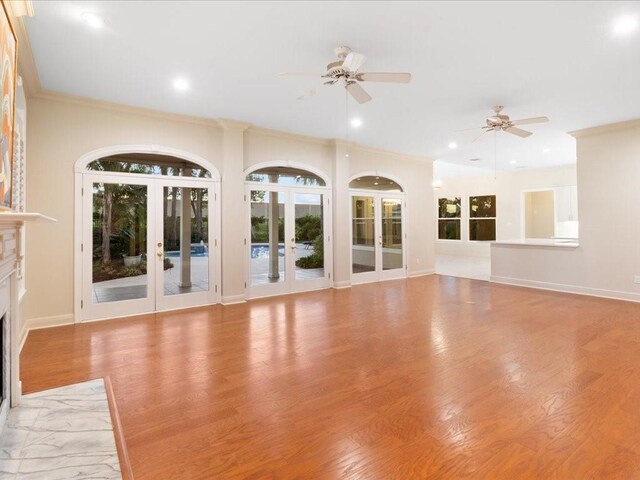 unfurnished living room with ceiling fan, light wood-type flooring, ornamental molding, and french doors