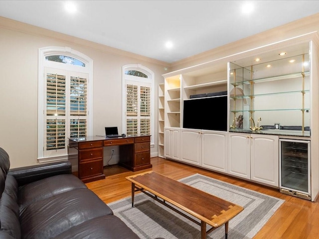 living room featuring bar area, wine cooler, crown molding, and light hardwood / wood-style floors