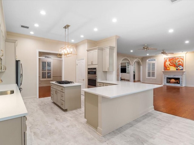 kitchen featuring a center island, sink, stainless steel appliances, hanging light fixtures, and kitchen peninsula