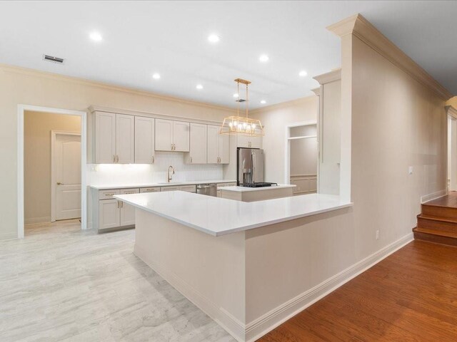 kitchen featuring sink, hanging light fixtures, appliances with stainless steel finishes, light hardwood / wood-style floors, and white cabinetry