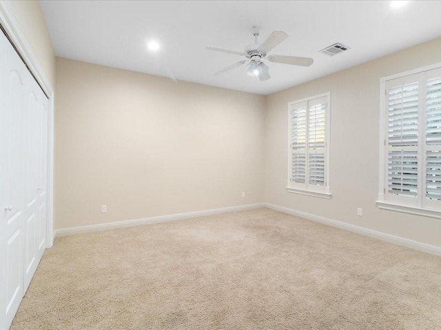 empty room with ceiling fan and light colored carpet