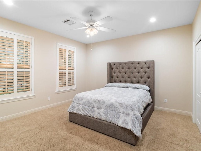 bedroom with ceiling fan, light carpet, and multiple windows