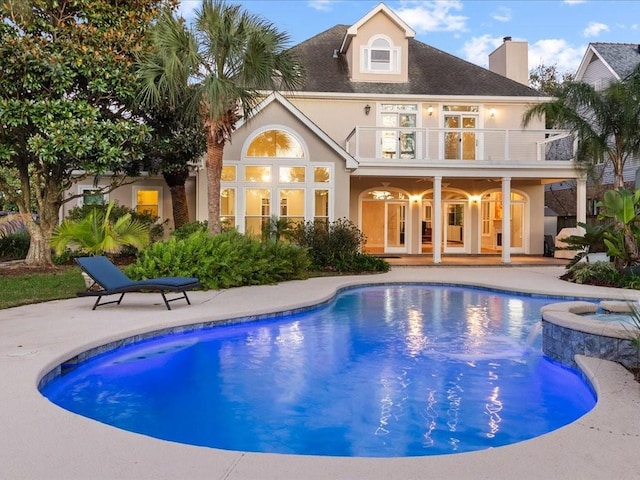 rear view of property featuring a pool with hot tub, a patio area, a balcony, and ceiling fan