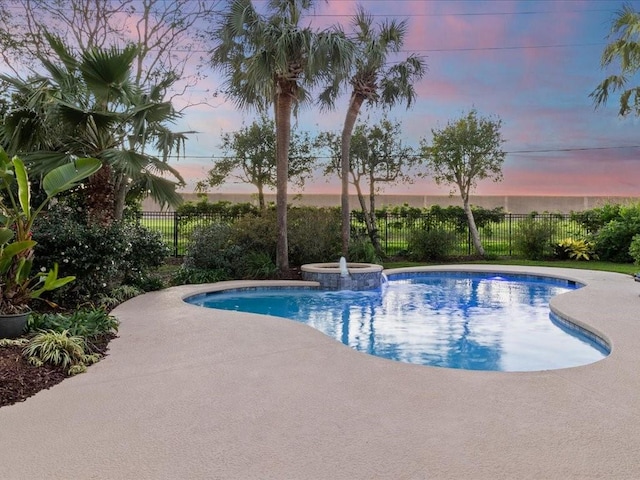 pool at dusk featuring an in ground hot tub