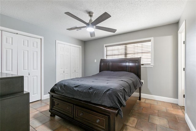 bedroom featuring a textured ceiling, ceiling fan, and multiple closets