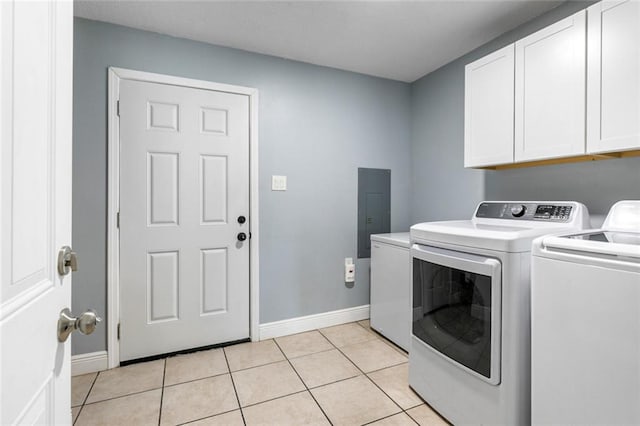 washroom featuring electric panel, washer and clothes dryer, light tile patterned floors, and cabinets