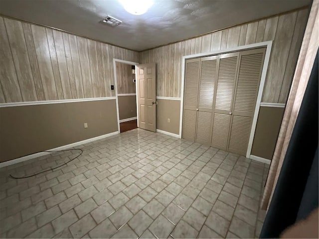 unfurnished bedroom featuring wooden walls and a closet