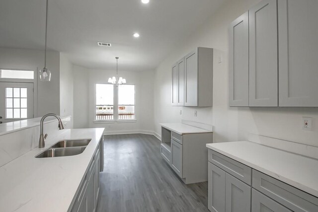 kitchen featuring light wood-type flooring, gray cabinetry, sink, decorative light fixtures, and a chandelier