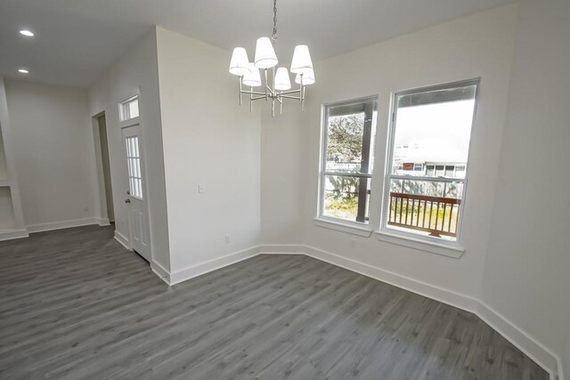 unfurnished dining area with a chandelier and dark hardwood / wood-style floors