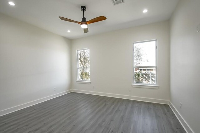 spare room with a wealth of natural light, ceiling fan, and dark wood-type flooring