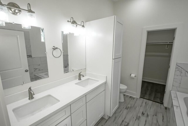 bathroom featuring hardwood / wood-style floors, vanity, toilet, and a tub