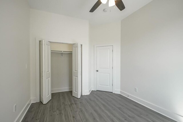 unfurnished bedroom featuring ceiling fan, a closet, and wood-type flooring