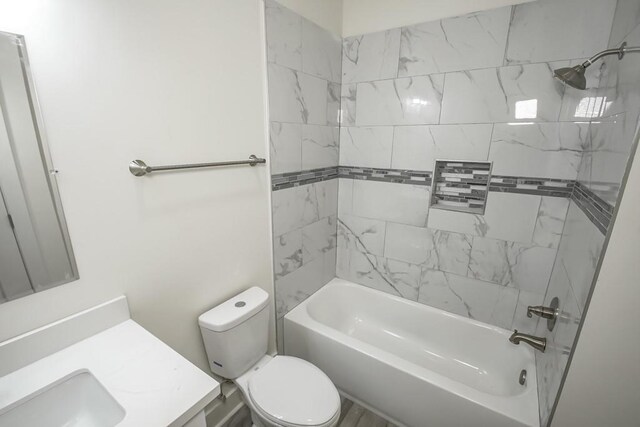 full bathroom featuring vanity, tiled shower / bath combo, and toilet