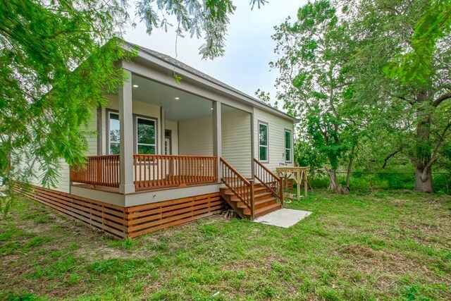 rear view of house featuring a lawn and covered porch