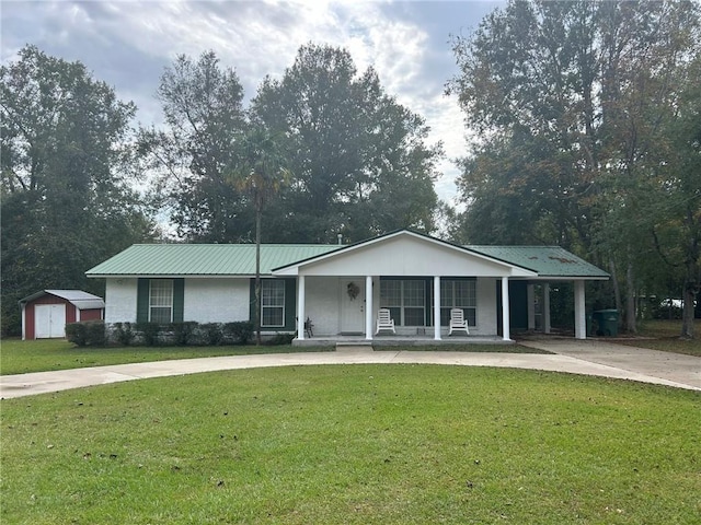 ranch-style home featuring metal roof, an attached carport, concrete driveway, and a front yard