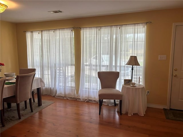 sitting room featuring a wealth of natural light, visible vents, and wood finished floors