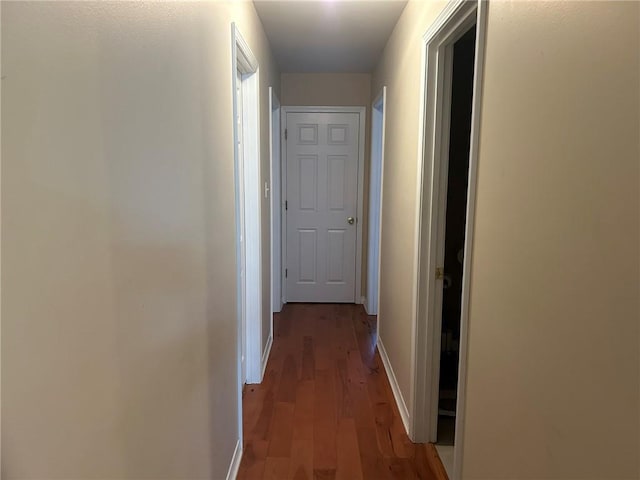 corridor featuring baseboards and wood finished floors