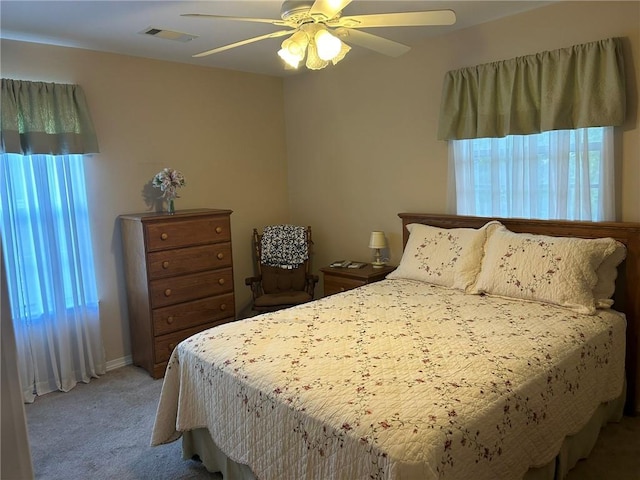 bedroom featuring light carpet, visible vents, baseboards, and ceiling fan