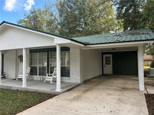 view of home's exterior with an attached carport, brick siding, metal roof, and concrete driveway