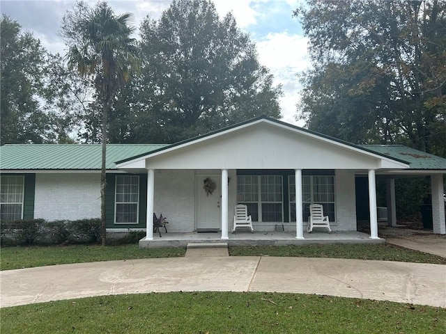 view of front of house featuring a carport, covered porch, brick siding, and metal roof