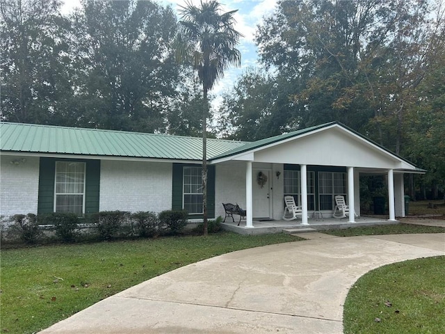 single story home featuring brick siding, driveway, metal roof, and a front lawn