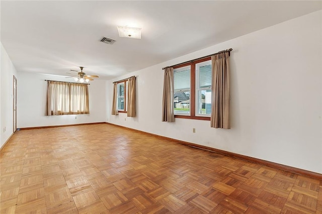 empty room with ceiling fan, a healthy amount of sunlight, and parquet flooring