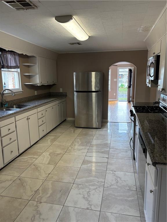 kitchen featuring white cabinets, stainless steel appliances, dark stone countertops, and sink