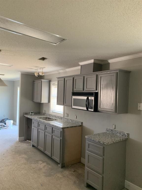 kitchen with a textured ceiling, gray cabinetry, and sink