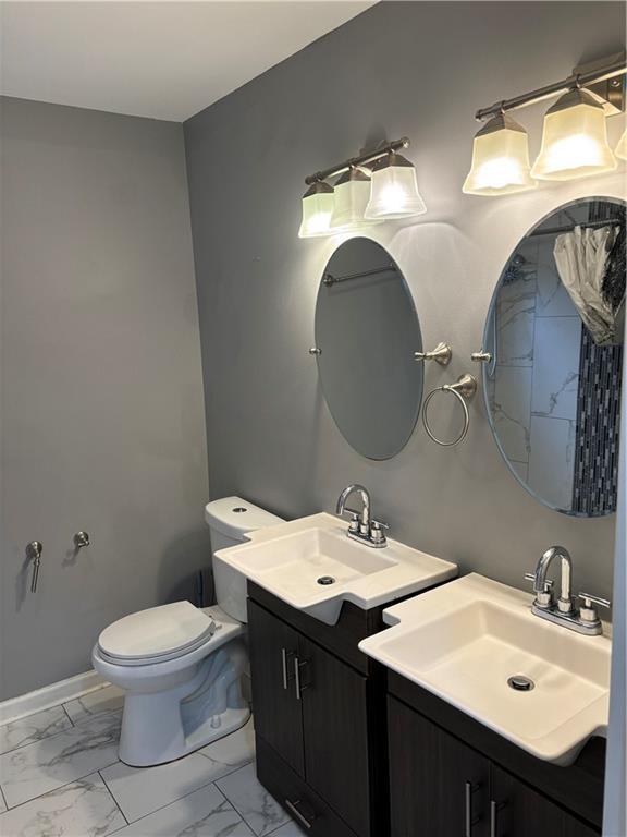 610 W Dr, Westwego, LA 70094 - bathroom with marble look tiles, two vanities, toilet, and baseboards