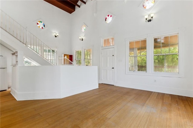 unfurnished living room with plenty of natural light, high vaulted ceiling, and hardwood / wood-style flooring