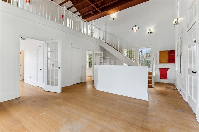 unfurnished living room featuring light hardwood / wood-style flooring and a towering ceiling