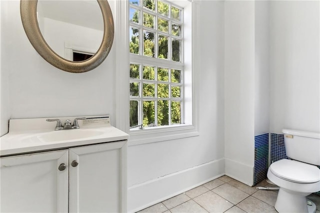 bathroom with tile patterned floors, vanity, toilet, and a wealth of natural light