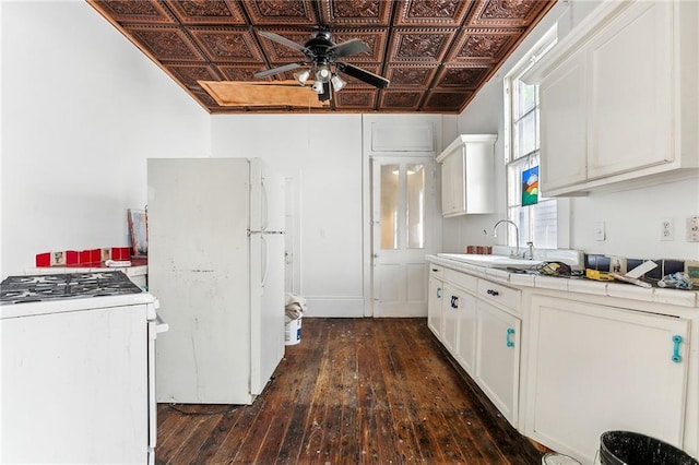 kitchen with tile countertops, white appliances, dark wood-type flooring, sink, and white cabinetry