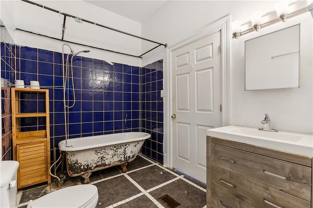 bathroom with vanity, toilet, and tile walls