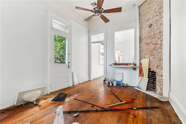 entrance foyer featuring ceiling fan, hardwood / wood-style floors, and brick wall