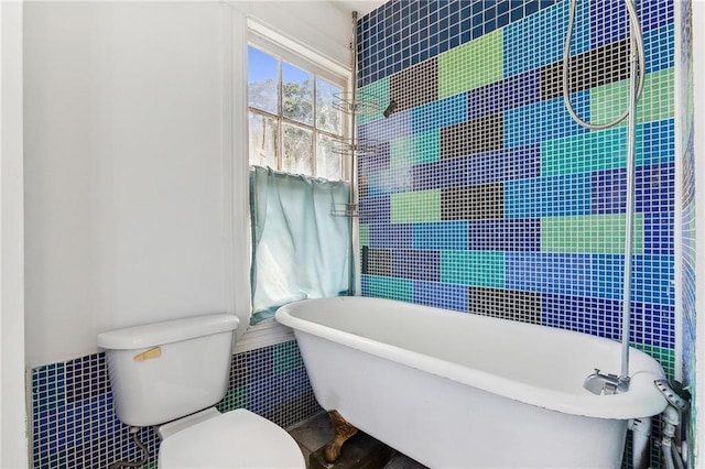 bathroom with a bathtub, toilet, and tile walls