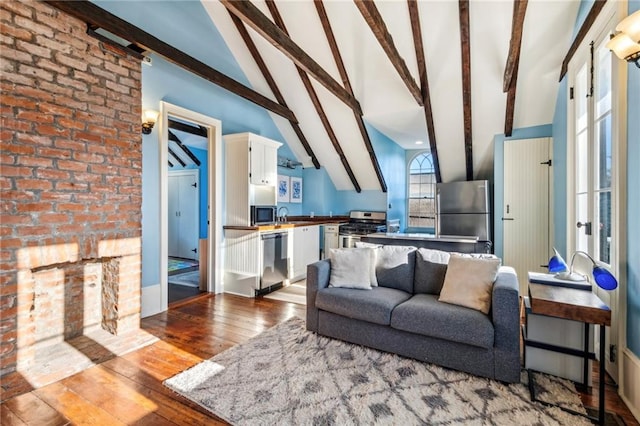 living room with high vaulted ceiling, light hardwood / wood-style floors, beam ceiling, and brick wall