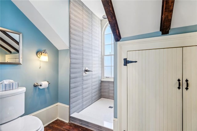 bathroom featuring a tile shower, vaulted ceiling with beams, toilet, and hardwood / wood-style flooring